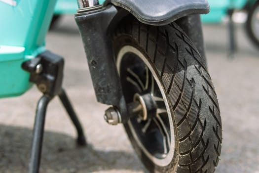 front wheel from an electric scooter close-up, the scooter stands on a leg on the street. High quality photo