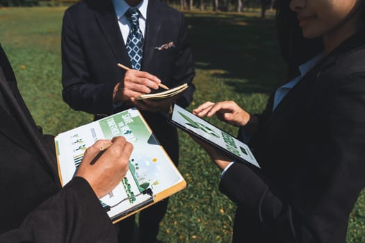 Group of asian business people presenting environmentally friendly development plan and sustainable technology project for greener future, establishing outdoor eco business office at natural park.Gyre