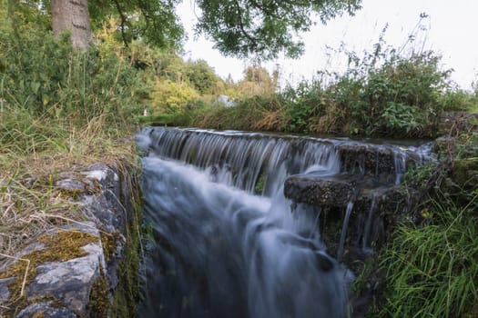 a small waterfall from a mountain river flows through the forest, close-up. A beautiful landscape of wild nature. High quality photo