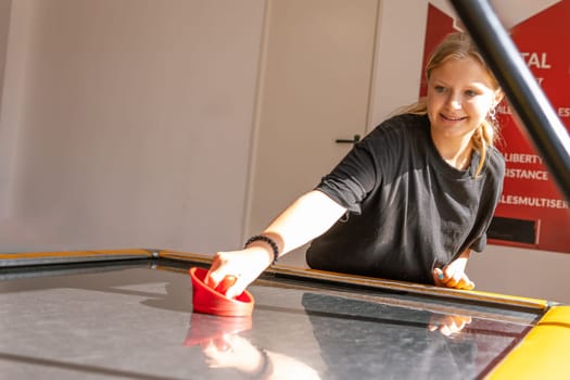 Cute teen girl plays air hockey arcade in game machine at an amusement park. High quality photo