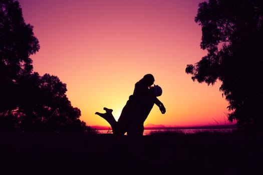 silhouette of a couple in love at sunset against the backdrop of nature, there is a place for the inscription, the guy is holding the girl in his arms, a happy couple silhouette. High quality photo