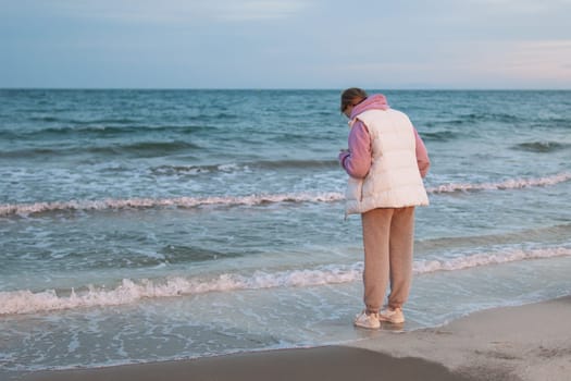 A young girl standing alone near the coast of the sea ocean. Fresh spring morning and dramatic sky. High quality photo