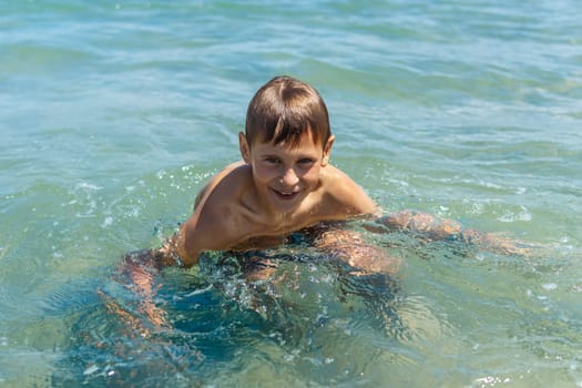 Happy boy swims and dives underwater. Active healthy lifestyle, water sports and activities with parents on summer family vacation with child. High quality photo