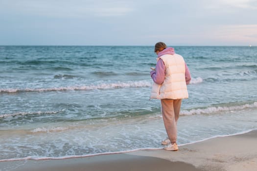 Portrait of a girl by the sea. girl in casual clothes. A woman is standing near the water. is dreaming. Sad girl by the sea. A woman stands by the sea is sad and looks at the sea High quality photo