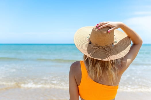 portrait of a girl with her back turned to the camera, close-up, the girl is standing in a brown hat and swimsuit, there is a place for an inscript. High quality photo