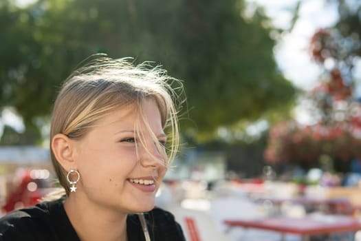 portrait of a teenage girl of European appearance with blond hair. The girl smiles and looks to the side. There is a place for an inscription. High quality photo