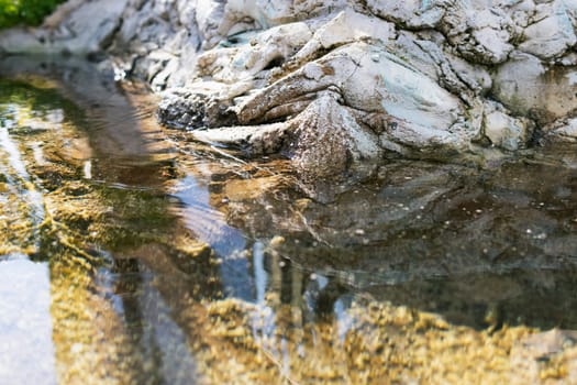 a stream in a forest with clear water near a mountain of stones, close-up. High quality photo