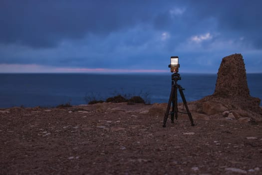 the phone on a tripod stands at dawn on a mountain by the sea and photographs the dawn. Beautiful seascape has a place for an inscription. High quality photo