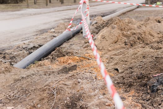 Plastic pipes in the ground during construction on the street. excavated road fenced with signal tape.High quality photo