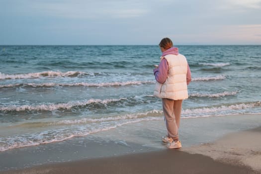 A teenager communicates on the phone with a guy and is sad while standing near the sea, the concept of a difficult age in teenagers. High quality photo