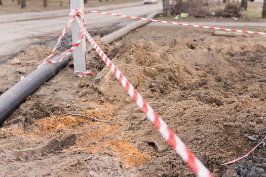 Plastic pipes in the ground during construction on the street. excavated road fenced with signal tape.High quality photo