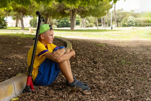 teenager in casual clothes sitting in the park on a scooter relaxing, active lifestyle of a child. High quality photo