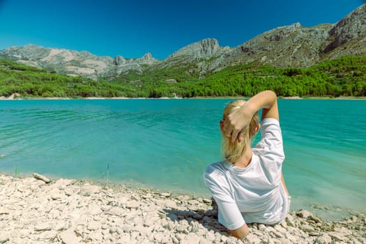 The girl lies admiring the beautiful mountain landscape, A beautiful mountain landscape, a view of the mountains and a lake with turquoise water, there is a place for an inscription.High quality photo