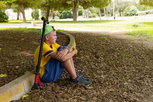 teenager in casual clothes sitting in the park on a scooter relaxing, active lifestyle of a child. High quality photo