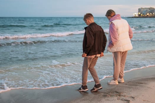 Brother and sister of European appearance are standing on the beach near the sea walking,family vacation in spring.Beautiful seascape with children. High quality photo