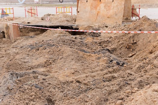 the ground during construction on the street. excavated road fenced with signal tape.High quality photo