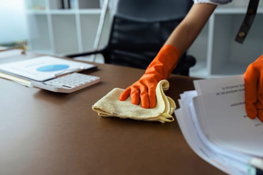 Woman maid cleaning and wiping the table with microfiber cloth in office.