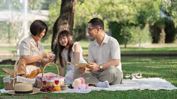 happy smiling family grandparent and grandchild picnic together outside at park.