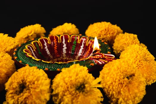 Diwali's charm captured, A radiant Diwali lamp and ornate flower rangoli on a striking black background. Perfect for festive invitations, ceremonies, and celebrations.