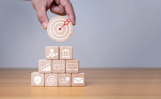 Businessman's hands hold a circular wooden board with printed target icons, business goals and objectives concept, business competition.