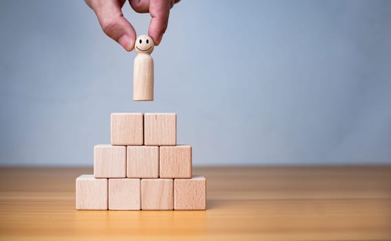 Business and HR concept for leaders and team leaders, human hand holding a wooden doll placed on a wooden block.