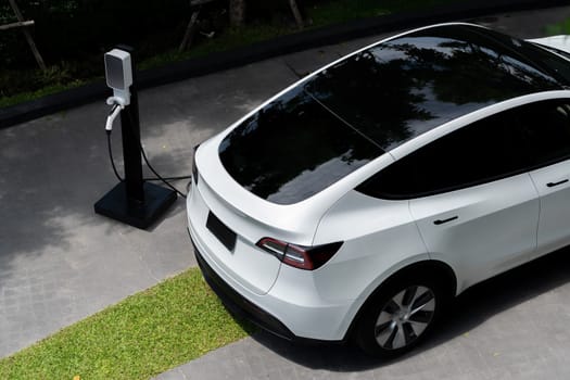 EV electric car charging in green sustainable city outdoor garden in summer. Urban sustainability lifestyle by green clean rechargeable energy of electric BEV vehicle innards