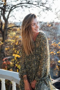 woman in a dress stands at the railing in the park on the street walk