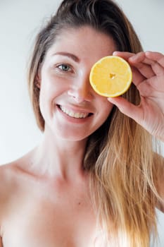 portrait of woman with an orange by the eye smiling