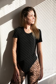 woman in a black swimsuit bodysuit with a shadow on her face