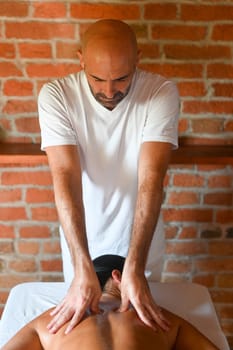 hispanic brunette adult fit woman enjoy massage by physiotherapist in the therapeutical bed at the spa