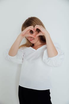 woman in white made a heart out of her fingers and looks into it