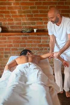 hispanic brunette adult fit woman enjoy massage by physiotherapist in the therapeutical bed at the spa