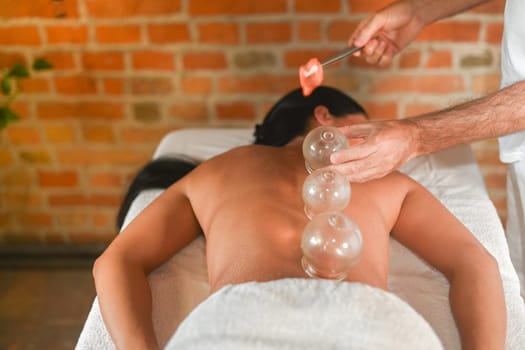 physiotherapist perform cupping therapy with suction massage to hispanic adult fit woman in the therapeutical bed for stress relief