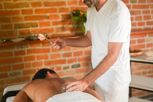 physiotherapist perform cupping therapy with suction massage to hispanic adult fit woman in the therapeutical bed for stress relief