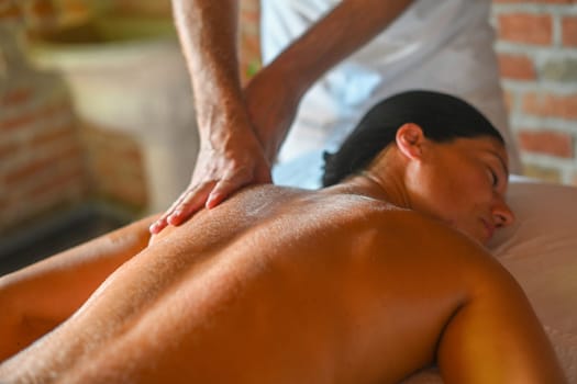 hispanic brunette adult fit woman enjoy massage by physiotherapist in the therapeutical bed at the spa