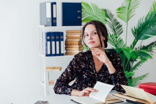 business woman sits in an office with a stack of books