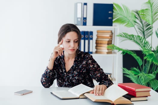 woman in the office sits at a desk reading a book