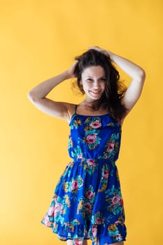 a cheerful woman in a blue floral dress on a yellow background