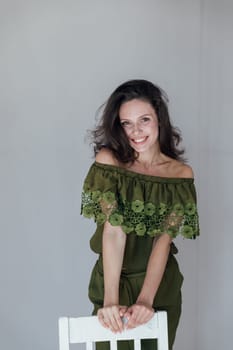 brunette woman in green clothes leaned on a chair