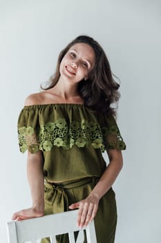 brunette woman in green clothes leaned on a chair