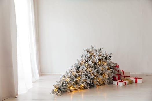 Christmas tree with garlands lies on the floor in the room with gifts new year decoration