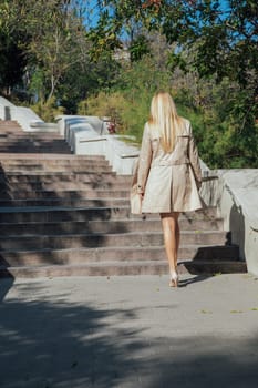 woman in a cloak walks in the park walking to the stairs