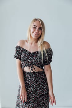 a beautiful blonde in colored clothes poses on a white background