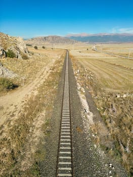 Top view of the train track passing through the arid land, taken with a drone