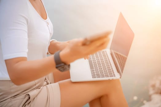 Freelance close up woman hands writing on computer. Well looking middle aged woman typing on laptop keyboard outdoors with beautiful sea view