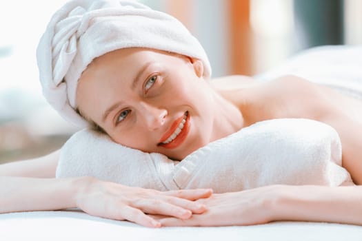 A beautiful young woman lies on a spa bed, her body relaxed and at peace. Pretty caucasian girl surrounded by the spa environment and the gentle aroma of essential oils. Close up. Tranquility.