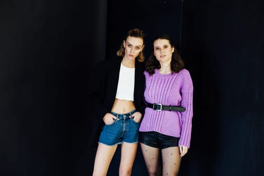 two fashionable women models pose on dark background