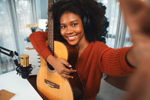 Host channel in musician of young African American with selfie for fans, broadcasting on smartphone in private studio. Decoration of equipment of headsets and recording microphone. Tastemaker.