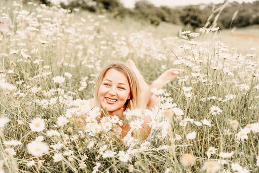 A woman lies in a chamomile field, dressed in a white dress.