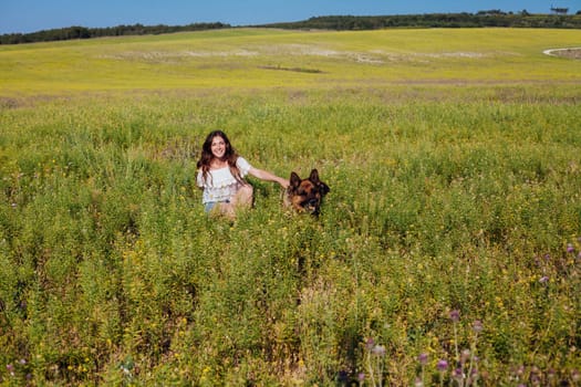 woman with a dog shepherd sitting in a green field